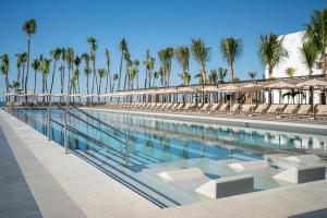 a swimming pool with chairs and palm trees at Riu Flamingos - All Inclusive in Nuevo Vallarta