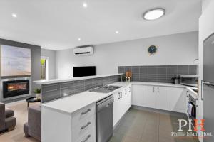 a kitchen with white cabinets and a fireplace at Townhouse with Shared Pool in Cowes in Cowes
