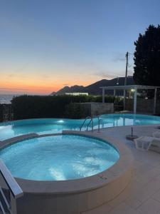 a large swimming pool with a sunset in the background at Sea Whisper Villa in Dobra Voda