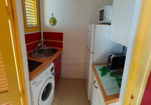 a small kitchen with a refrigerator and a washing machine at Hauts de Caritan in Sainte-Anne