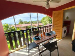 a dining room with a table and chairs on a balcony at Hauts de Caritan in Sainte-Anne