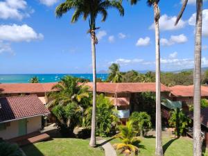 a view of the ocean from the balcony of a resort with palm trees at Hauts de Caritan in Sainte-Anne