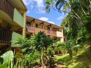 a yellow building with trees in front of it at Hauts de Caritan in Sainte-Anne