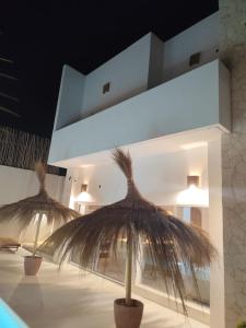 two straw umbrellas in front of a building at Villa Face a l'océan- Havre de paix & grand confort avec piscine à TOUBAB DIALAW in Rufisque