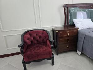 a red chair next to a bed and a dresser at Charming Studio in Golden Triangle in Harare