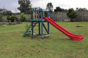 a playground with a red slide in a yard at Saints boutique lodge in Bloemfontein