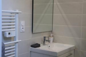 a white bathroom with a sink and a mirror at Appartement neuf climatisé in Aramits