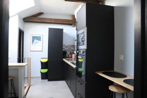 a kitchen with black and white cabinets and a counter at Appartement neuf climatisé in Aramits