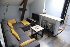 a living room with a couch and a table and a kitchen at Appartement neuf climatisé in Aramits