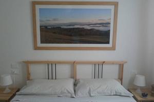un quadro appeso sopra un letto con due cuscini di La Medialuna a Montespertoli