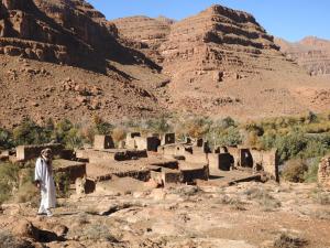 a man standing in front of a village in the desert at Gîte Palma Eagle Ziz Canyon in Er Rachidia