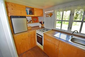 a kitchen with wooden cabinets and a stove and a sink at "Björkhorva" in Vimmerby