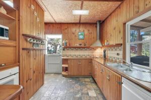 a kitchen with wooden walls and a sink and a window at Aloha Amity in Amity Point +8 photos