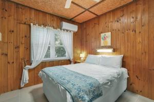 a bedroom with a bed with wooden walls and a window at Aloha Amity in Amity Point