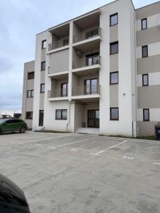 a large white apartment building with a parking lot at L&D Apartments in Urseni