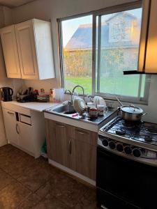 a kitchen with a stove and a sink and a window at Casa Maybell in Chillán