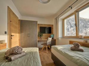 a bedroom with two beds and a desk and a window at Lodge am Wetterstein in Ehrwald
