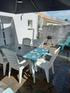 a table and chairs on a patio with an umbrella at Maison agréable à Oléron in Dolus-d'Oléron