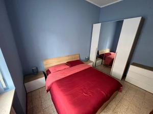a bedroom with a red bed and two mirrors at La porta sul Viale in Cuneo