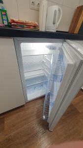 an empty refrigerator with its door open on a wooden floor at Monteurzimmer 05 in Parchim in Parchim