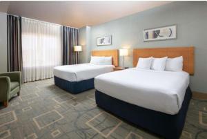 a hotel room with two beds and a chair at The Platinum Hotel Las Vegas in Las Vegas