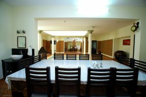 a dining room with a large table and chairs at Malakkarethu House in Aranmūla