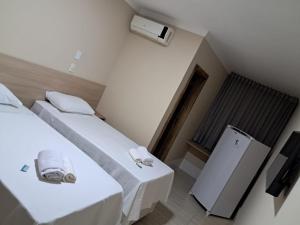 a small room with two beds and a refrigerator at Cristal park flats in Cristalina