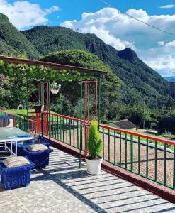 a deck with a table and chairs and mountains at Hotel Cerro Fuerte breakfast & eventos in Sopó