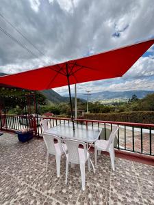 a table and chairs with a red umbrella at Hotel Cerro Fuerte breakfast & eventos in Sopó