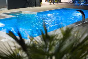 a large blue swimming pool with a curved plunge at Villa De Luxe Infinity in Bihać