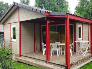 a red and white shed with a table on a deck at Chalet 4 pers avec Terrasse à Capvern - API-1-52-1745 in Capvern