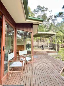 a house with a wooden deck with a table and benches at Halls Gap House in Halls Gap