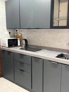 a kitchen with white cabinets and a microwave at فندق ليمة الذهبي in Mecca
