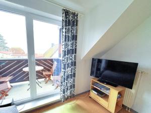 a living room with a television and a balcony at Fewo Weitblick - helle Wohnung, 2 SZ, Wasserblick in Breege