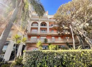 a large building with palm trees in front of it at Victoria Palace T2 de 50m2 in Menton
