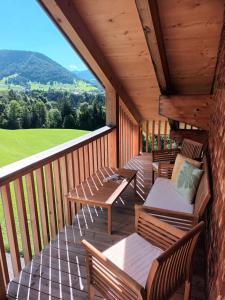 a porch with wooden chairs and tables and a view at Haus Hagspiel in Hittisau