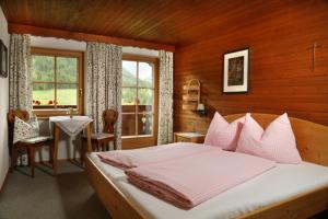 a bedroom with a bed and a table and a window at Bauernhof im Wiesengrund in Maria Luggau