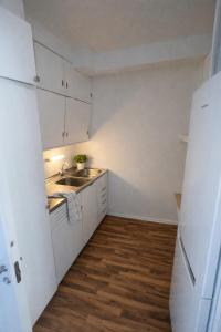a small kitchen with white cabinets and a sink at Eide Apartments Odda in Odda