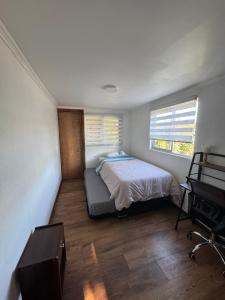 a small bedroom with a bed and a desk at Casa Maybell in Chillán