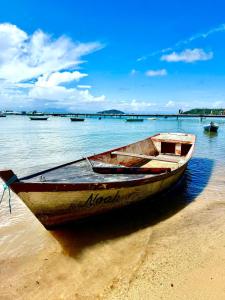 a wooden boat sitting on the sand on the beach at Casa Praiana Búzios in Búzios