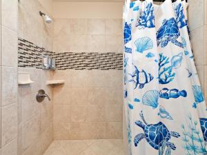a bathroom with a shower with a blue and white shower curtain at #04 Black Sand Beach Condo in Pahala +16 photos