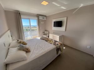 a bedroom with a large bed and a window at Hotel Jardim do Mar in Torres