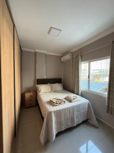 a bedroom with a bed and a large window at Apartamento 3 quartos próximo à praia central de BC in Balneário Camboriú