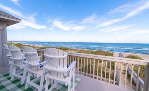 a row of chairs on a balcony overlooking the beach at Looking Glass - Nags Head MP 12, Oceanfront, Ocean View, Pool, Hot Tub, Pets OK, Flex Stays in Nags Head