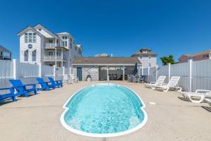 a swimming pool with chairs and a fence and a house at Looking Glass - Nags Head MP 12, Oceanfront, Ocean View, Pool, Hot Tub, Pets OK, Flex Stays in Nags Head