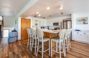 a kitchen with a bar with white stools around it at Looking Glass - Nags Head MP 12, Oceanfront, Ocean View, Pool, Hot Tub, Pets OK, Flex Stays in Nags Head +57 photos