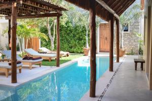 an outdoor pool with a pergola and a house at Casa Boutique Coco Calin in Sisal
