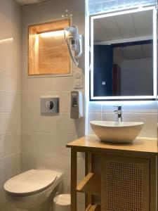 a bathroom with a sink and a toilet and a mirror at Hôtel Angelic in Lourdes