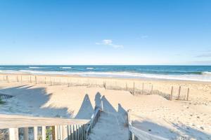 a sandy beach with a fence and the ocean at Sea Reunion - Nags Head MP 12.5, Oceanfront, Amazing Views! Pool, Hot Tub, Pets OK in Nags Head