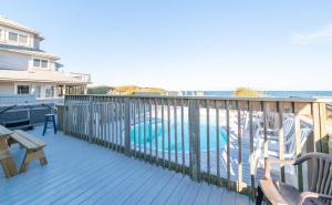 a deck with a table and chairs and a swimming pool at Sea Reunion - Nags Head MP 12.5, Oceanfront, Amazing Views! Pool, Hot Tub, Pets OK in Nags Head
